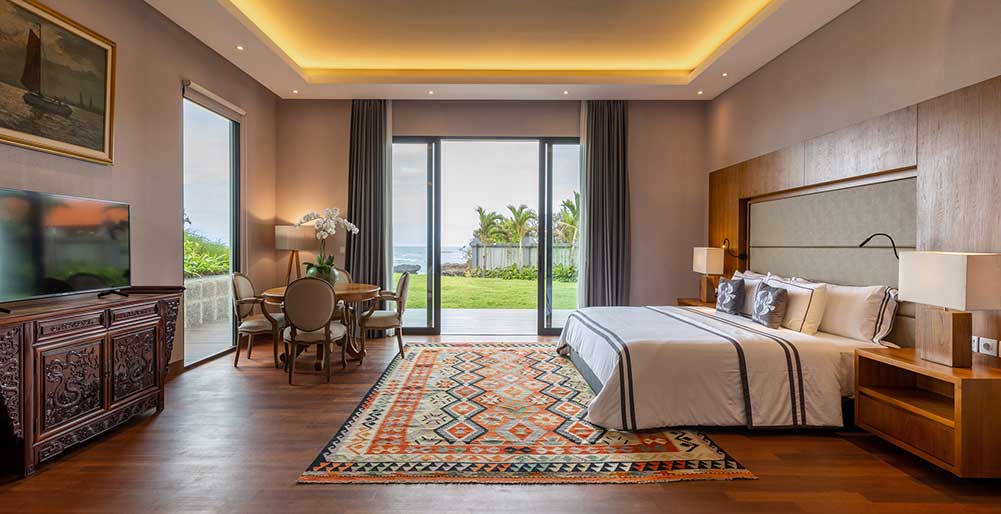 Tirtha Bayu Villa I - Deluxe Suite bedroom with seating area and garden access